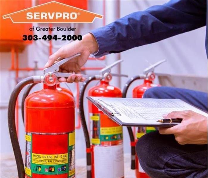 Man grabbing a fire extinguisher with SERVPRO of Greater Boulder logo